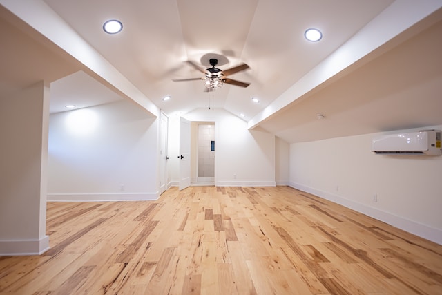 additional living space featuring light wood-type flooring, vaulted ceiling, an AC wall unit, and ceiling fan