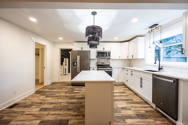 kitchen featuring appliances with stainless steel finishes, a center island, decorative light fixtures, and sink