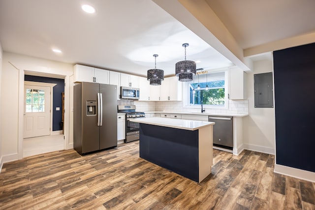 kitchen featuring appliances with stainless steel finishes, a kitchen island, a wealth of natural light, and dark wood-type flooring