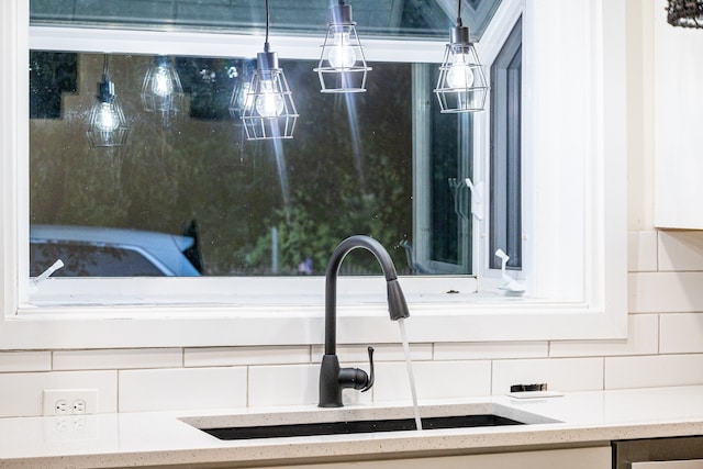 details featuring tasteful backsplash, light stone countertops, and sink