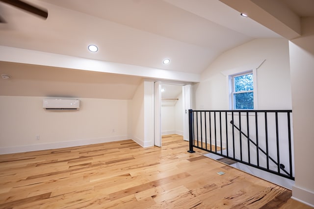 bonus room featuring light wood-type flooring, vaulted ceiling, and a wall mounted AC