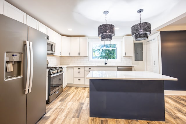 kitchen with sink, stainless steel appliances, white cabinets, pendant lighting, and a kitchen island