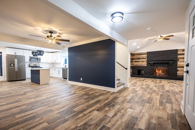 unfurnished living room with a fireplace, hardwood / wood-style flooring, ceiling fan, and lofted ceiling