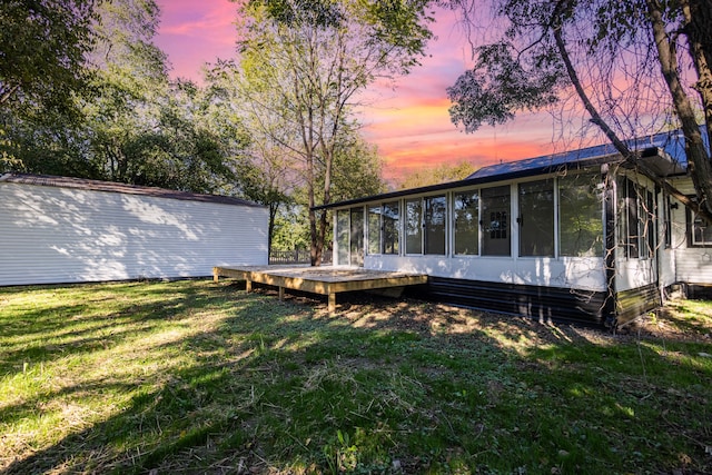 yard at dusk with a wooden deck and a sunroom