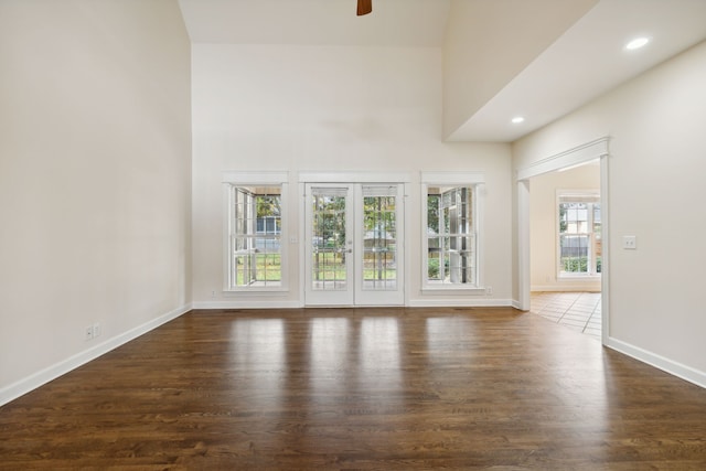 unfurnished living room with dark hardwood / wood-style flooring, ceiling fan, and a high ceiling