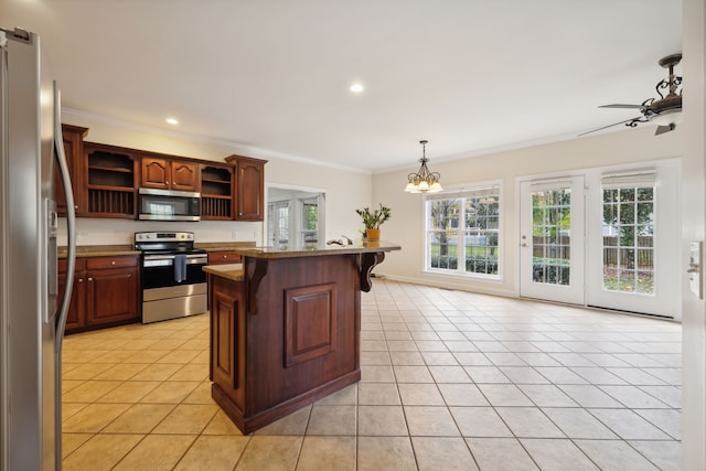 kitchen with hanging light fixtures, crown molding, light tile patterned floors, and appliances with stainless steel finishes