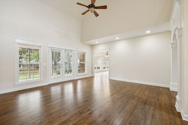 unfurnished living room featuring french doors, ornate columns, dark hardwood / wood-style floors, high vaulted ceiling, and ceiling fan