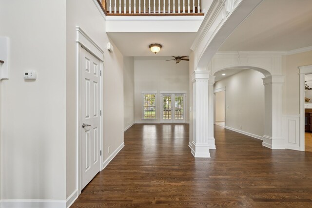 entryway with dark wood-type flooring, a towering ceiling, and decorative columns