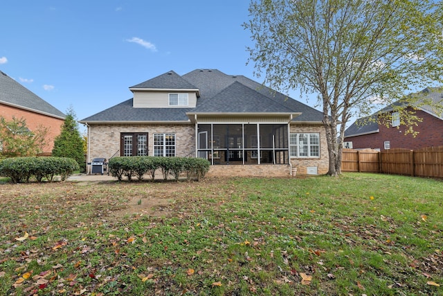 rear view of property featuring a sunroom and a lawn