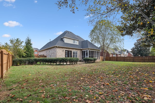 rear view of house featuring a lawn and a sunroom