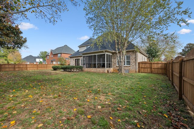 rear view of house featuring a sunroom and a yard