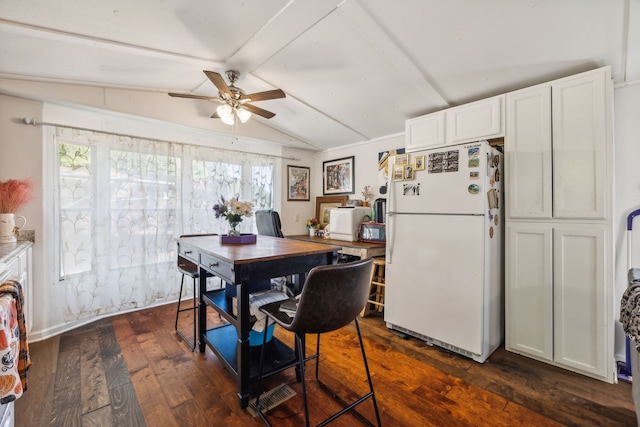 dining space featuring ceiling fan, vaulted ceiling with beams, and dark hardwood / wood-style flooring