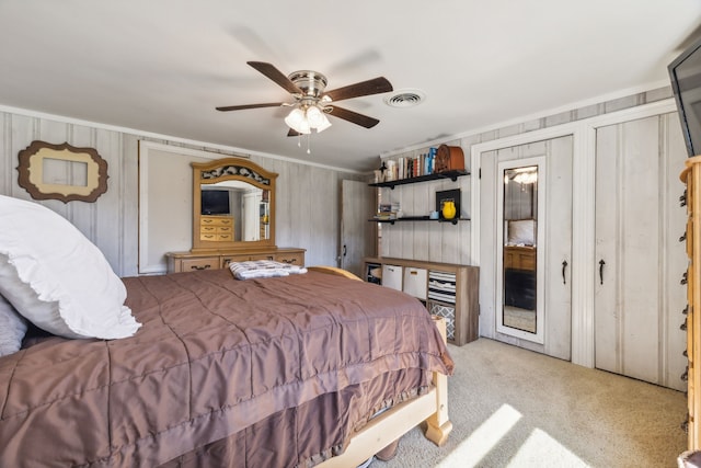 carpeted bedroom with crown molding, ceiling fan, and two closets