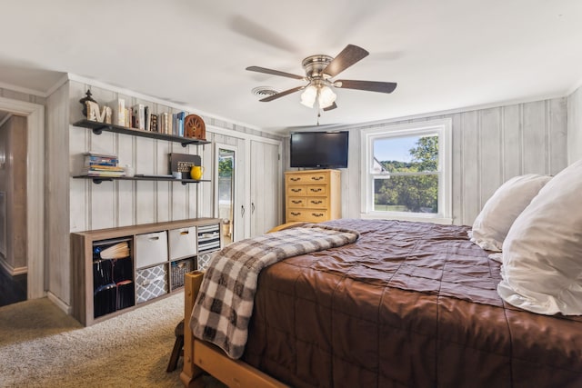 bedroom with ornamental molding, ceiling fan, wood walls, and carpet