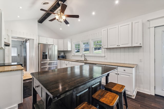 kitchen with stainless steel appliances, vaulted ceiling with beams, and white cabinetry