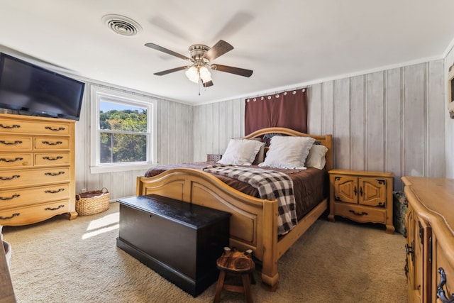 carpeted bedroom featuring ceiling fan and wooden walls