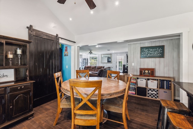 dining area with ceiling fan, dark wood-type flooring, a barn door, and high vaulted ceiling