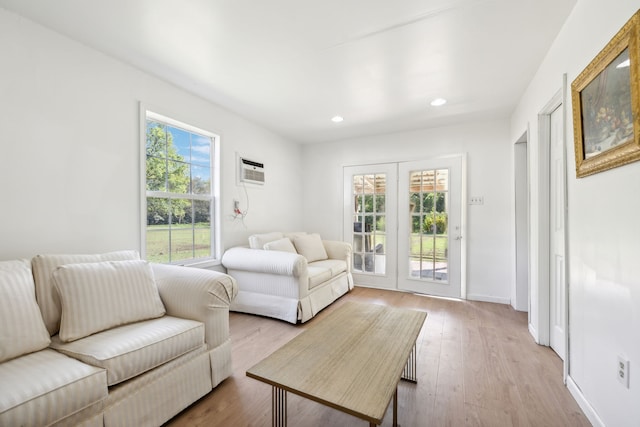 living room featuring a wealth of natural light, a wall mounted air conditioner, french doors, and light hardwood / wood-style flooring