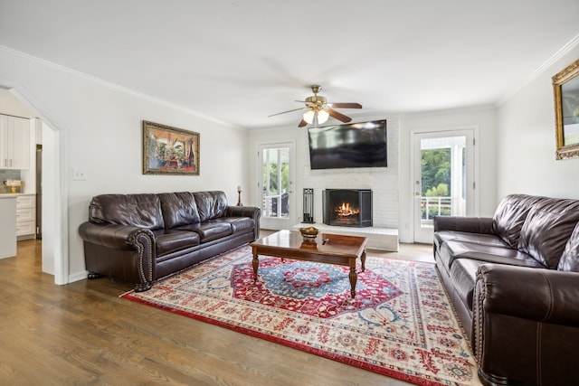 living room with ornamental molding, a fireplace, ceiling fan, and dark hardwood / wood-style flooring