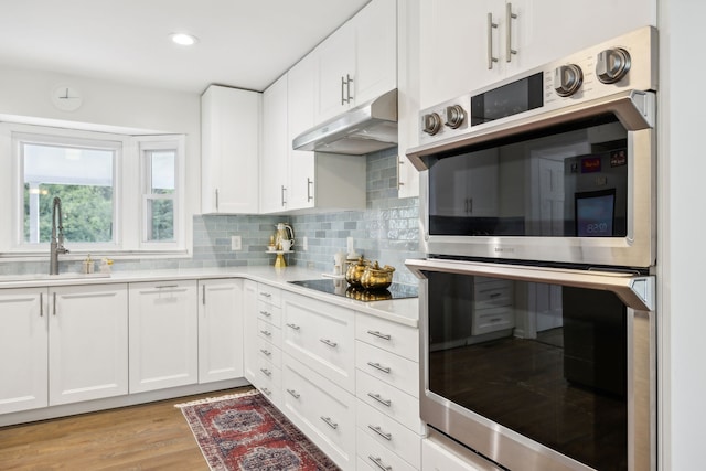 kitchen with white cabinets, sink, light hardwood / wood-style flooring, double oven, and black electric stovetop