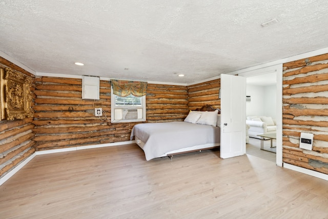 unfurnished bedroom with a textured ceiling, cooling unit, light wood-type flooring, and rustic walls