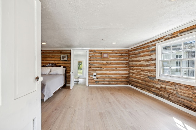 unfurnished bedroom featuring log walls, light hardwood / wood-style flooring, and a textured ceiling