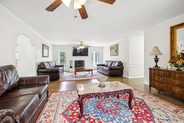 living room featuring dark wood-type flooring, crown molding, and ceiling fan