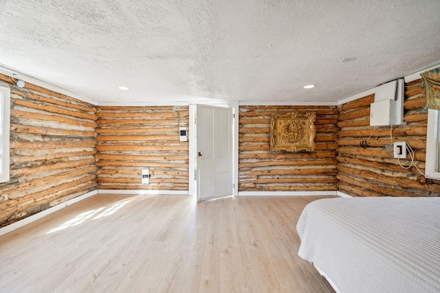 unfurnished bedroom featuring a textured ceiling, rustic walls, and light hardwood / wood-style floors