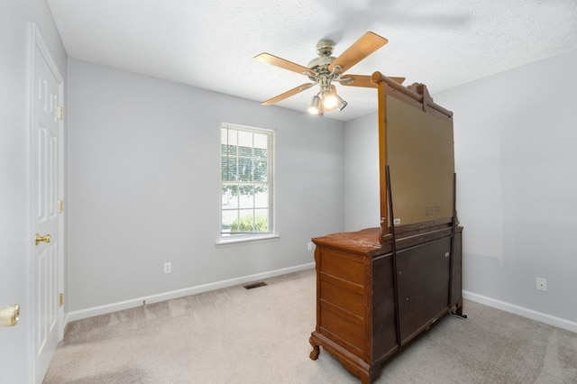 office area featuring ceiling fan, a textured ceiling, and light carpet