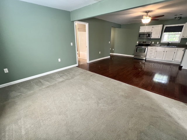 unfurnished living room with ceiling fan, dark wood-type flooring, and sink