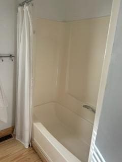 bathroom with hardwood / wood-style floors and shower / bathtub combination with curtain