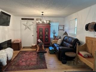 living room with an inviting chandelier, light hardwood / wood-style floors, and a textured ceiling