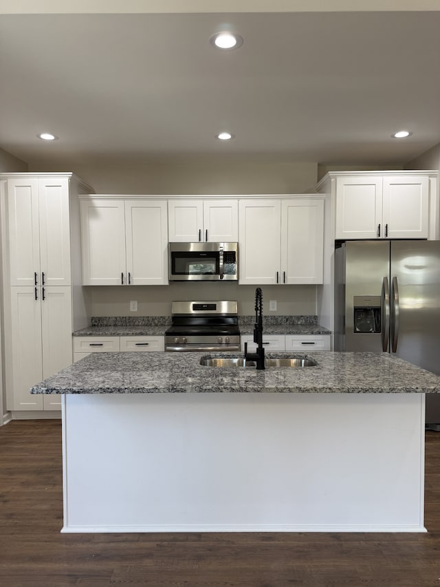 kitchen with white cabinets, sink, stainless steel appliances, dark hardwood / wood-style floors, and dark stone countertops