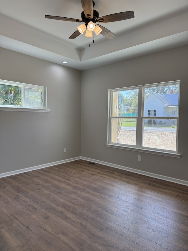 empty room featuring dark wood-type flooring, ceiling fan, and a healthy amount of sunlight