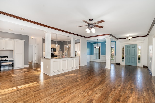 unfurnished living room with ceiling fan, ornate columns, crown molding, dark hardwood / wood-style flooring, and sink