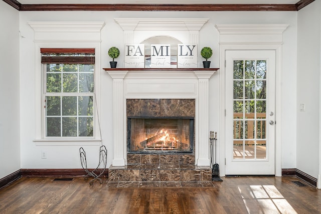 interior details featuring wood-type flooring, a tiled fireplace, and crown molding