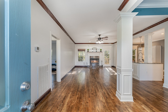 unfurnished living room featuring ceiling fan, dark hardwood / wood-style floors, ornate columns, and crown molding