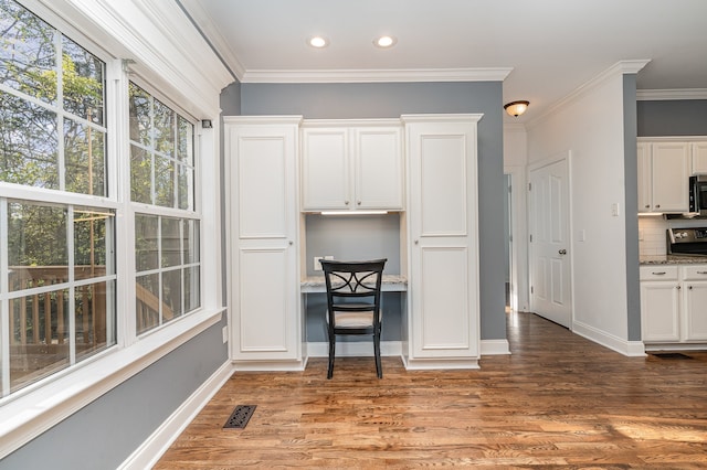 kitchen featuring stone countertops, wood-type flooring, decorative backsplash, ornamental molding, and white cabinetry