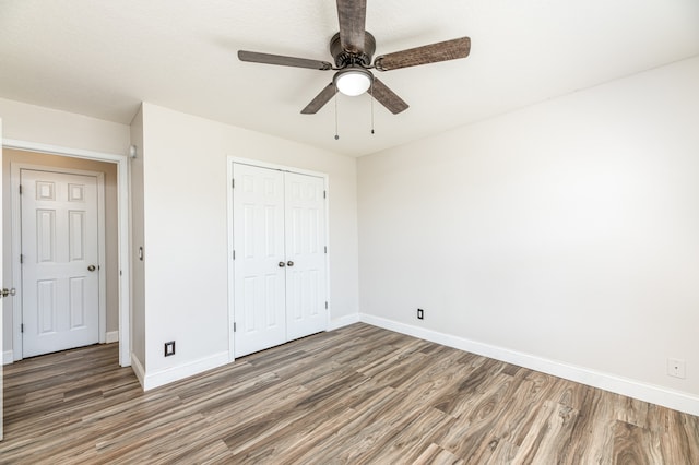 unfurnished bedroom with dark hardwood / wood-style flooring, a closet, and ceiling fan