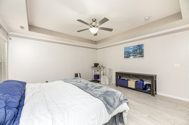 bedroom with light hardwood / wood-style floors, ornamental molding, a raised ceiling, and ceiling fan