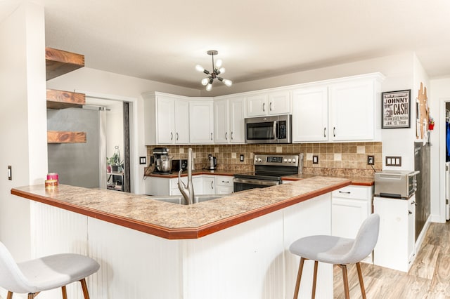 kitchen featuring white cabinetry, stainless steel appliances, a breakfast bar, and kitchen peninsula