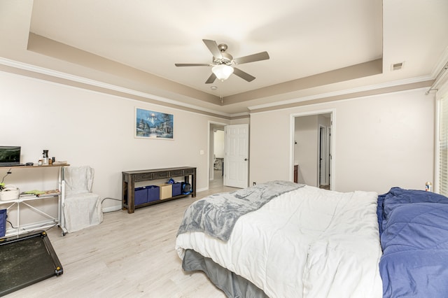 bedroom with ceiling fan, a raised ceiling, ornamental molding, and light hardwood / wood-style floors