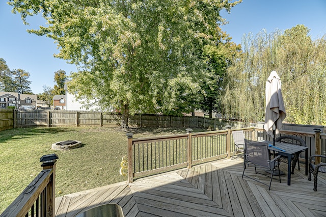 wooden terrace with an outdoor fire pit and a lawn