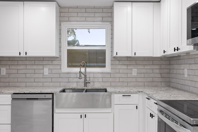 kitchen featuring light stone counters, sink, white cabinetry, appliances with stainless steel finishes, and decorative backsplash