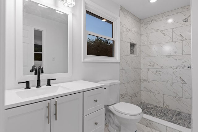 bathroom with vanity, toilet, and tiled shower