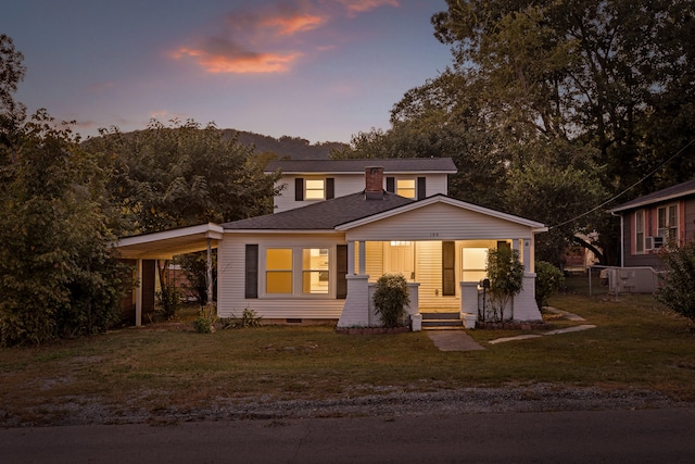 view of front of home with a yard, a porch, and a carport