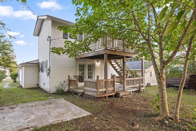 rear view of house featuring a wooden deck, a lawn, and a patio area