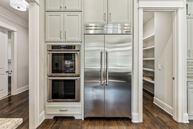 kitchen featuring light stone counters, white cabinetry, stainless steel appliances, and dark hardwood / wood-style flooring