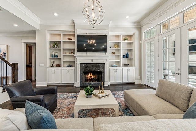 living room featuring a fireplace, crown molding, a notable chandelier, and dark wood-type flooring