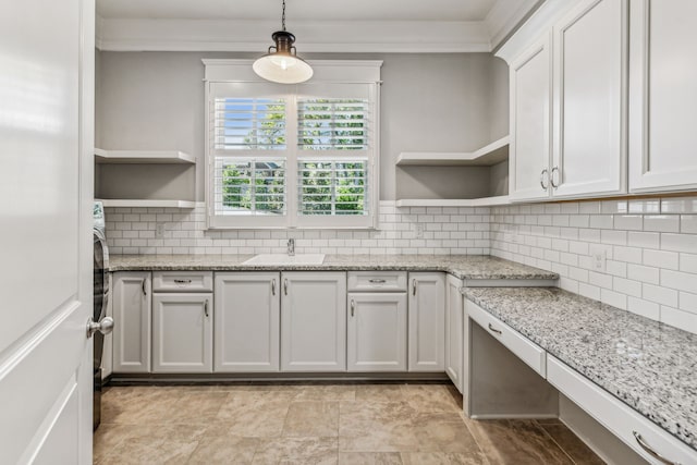 kitchen with backsplash, sink, light stone counters, hanging light fixtures, and white cabinets